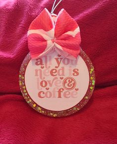 a red and white ornament with a pink bow on it that says all you need is love and coffee