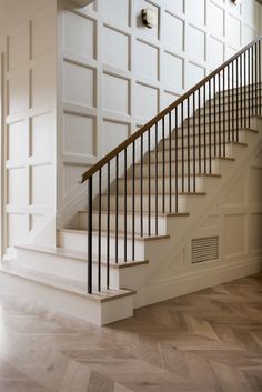 an empty room with white walls and wooden floors, stairs leading up to the second floor