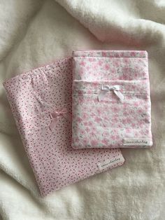 two pink and white cloths with bows on them sitting next to each other under a blanket