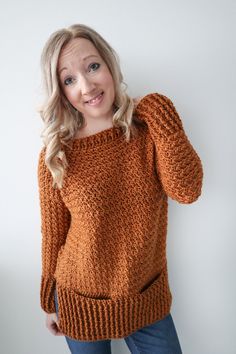 a woman in an orange sweater poses for the camera with her hand on her hip