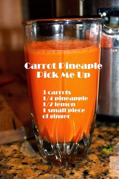 carrot pineapple pick me up recipe in a glass on the counter top next to an orange juicer