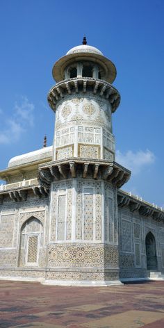 an ornate white building with arches and pillars on the outside, against a blue sky