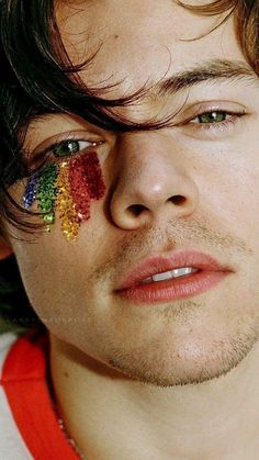 a young man with his face painted in rainbow colors and the word love is written on his forehead