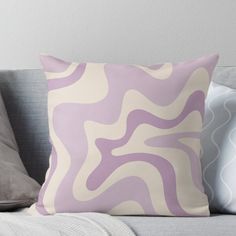 a purple and white pillow sitting on top of a couch next to a gray throw pillow