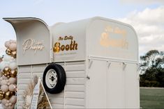 a white trailer with balloons attached to it's side and the words, happy birthday booth