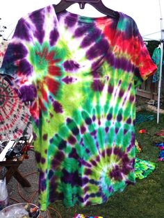 a tie - dyed shirt is hanging on a clothes line in front of other items