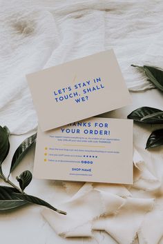 two business cards sitting next to each other on top of a white cloth covered bed