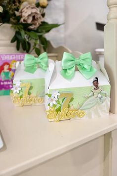 two small boxes with bows on them sitting on a table next to a vase filled with flowers