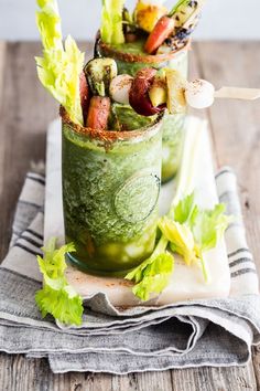 two glasses filled with different types of vegetables and garnishes on a napkin