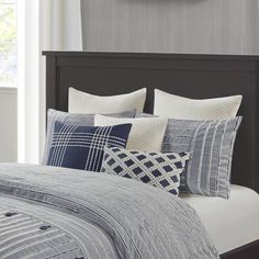 a bed with blue and white pillows on top of it in front of a clock