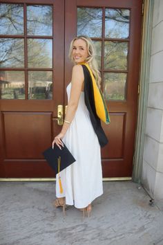 a woman standing in front of a door with her hand on her hip wearing a black and white dress