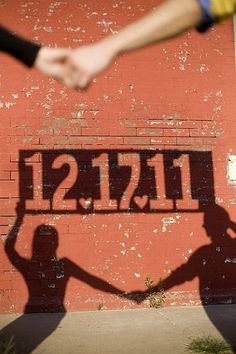 two people holding hands in front of a red wall