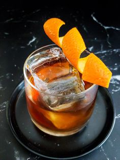 an old fashioned cocktail with orange peels on the rim and garnished with ice