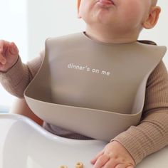 a baby sitting in a high chair with his hands on the table and eating food