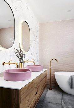 a bathroom with two sinks and a bathtub in the corner, along with a round mirror on the wall