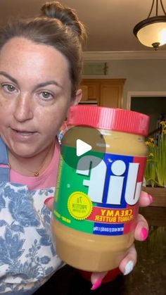 a woman holding up a jar of peanut butter