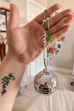 a person with a tattoo on their arm holding up a disco ball ornament