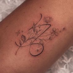 a woman's arm with flowers on it and the letter e in cursive writing