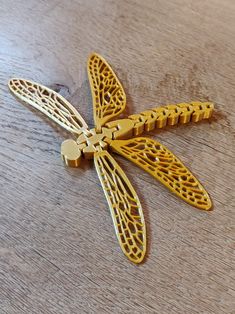 a yellow dragonfly brooch sitting on top of a wooden table