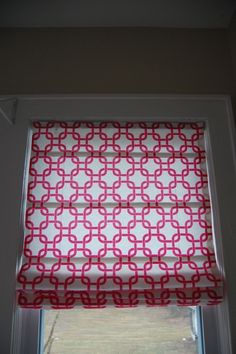 a red and white roman blind in front of a window