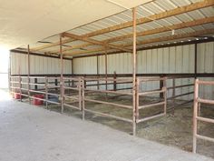 the inside of a barn with several stalls