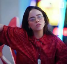 a woman wearing glasses and a red shirt is holding her arm up in the air