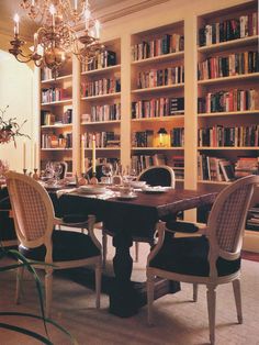 the dining room table is set with place settings for two people and there are many bookshelves in the background