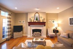 a living room filled with furniture and a fire place next to a tv mounted on a wall