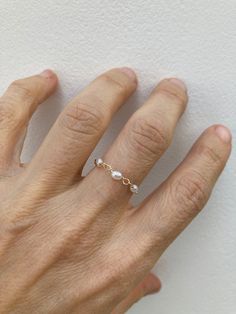 This little chain ring offers a fresh take on a traditional band ring. It is also very lightweight and comfortable to wear.  D E T A I L S *Made with AAA grade cultured freshwater rice pearls. These are very small measuring between 2- 4mm x 1.5mm. *Choose between a 14k gold filled or sterling silver chain. *Gold fill is a wonderful alternative to gold and unlike gold plating does not rub off. *Choose the size you prefer from the drop down menu.  *Ring comes with a matching crystal information ca Adjustable Dainty Rose Gold Pearl Ring, Adjustable Rose Gold Dainty Pearl Ring, Dainty 14k Rose Gold Pearl Ring, Dainty Pearl Chain Ring For Wedding, Dainty Wedding Pearl Ring With Pearl Chain, Gold Chain Ring, Rice Pearls, Freshwater Pearl Ring, Gold Filled Ring