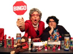 two people sitting at a table with various items on it and a sign that says binggo