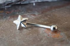 a silver nose piercing with a star design on it