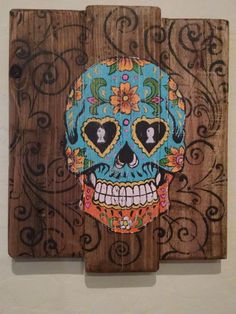 a wooden wall hanging with a colorful skull on it