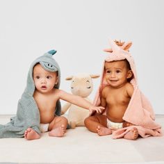 two babies sitting next to each other with towels on their heads and one holding a stuffed animal