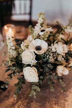 a bouquet of flowers sitting on top of a table next to two lit candle holders