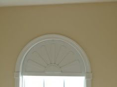 an arched window in the corner of a room with white trim on it's windowsill