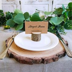 a place card holder is placed on top of a tree stump with a fork and knife