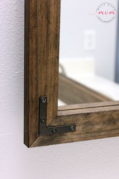 a mirror mounted to the side of a white wall next to a wooden framed window