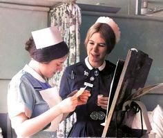 two women dressed in nurses uniforms looking at something on a table with papers and scissors