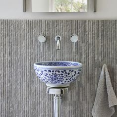 a blue and white bowl sink sitting under a bathroom mirror next to a towel rack