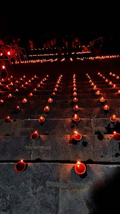 many candles are lit in rows on the ground