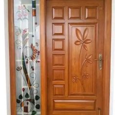 a wooden door with floral designs on the side and curtain behind it, in front of a white wall