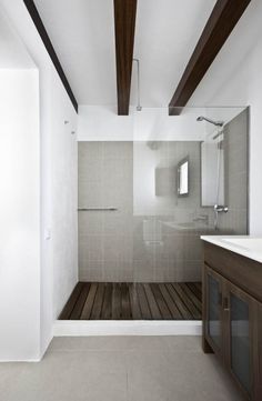 a bathroom with a wooden floor and white walls, along with a large walk in shower