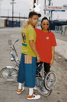 two people standing next to each other with bicycles