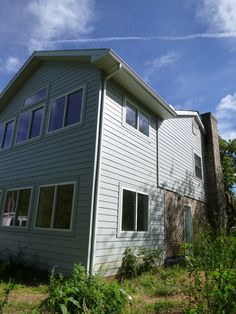 a large house sitting on the side of a lush green hillside under a blue sky