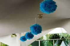 blue pom poms hanging from the ceiling in front of a white tent with palm trees