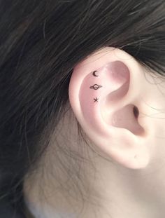 a woman's ear with two small stars and crescents on the middle of it