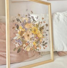 an image of a vase with flowers in it sitting on a bed next to pillows