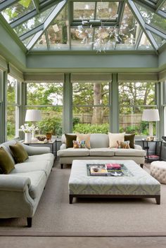 a living room filled with lots of furniture under a glass roof over a patio area