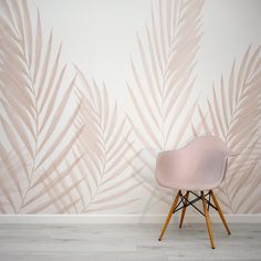 a pink chair sitting in front of a wall with palm leaves on it