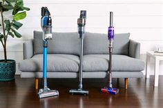 three different types of vacuums sitting on the floor in front of a gray couch